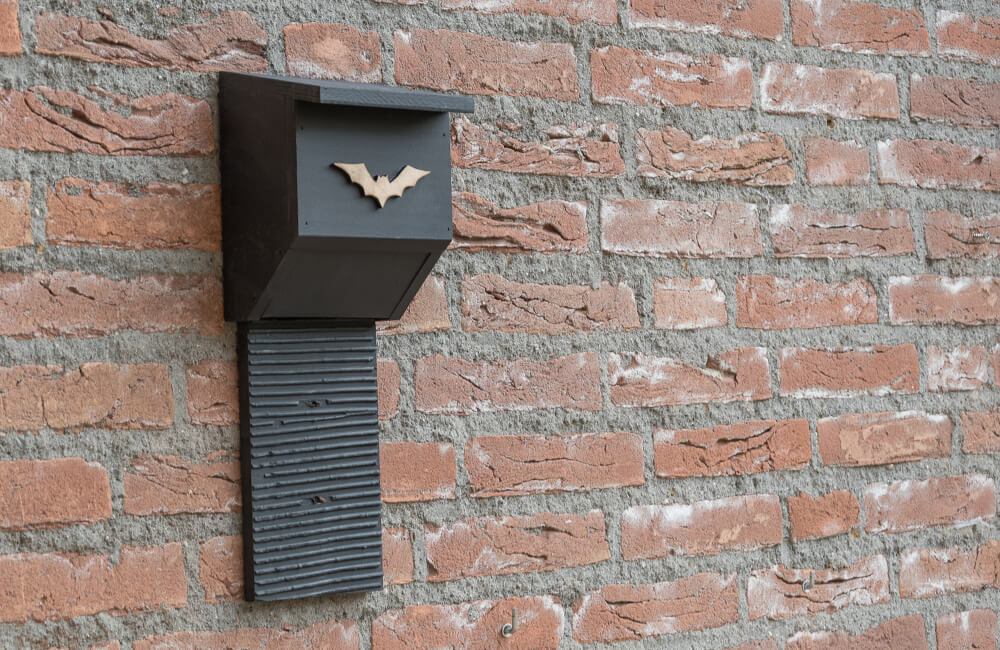 A decorative black bat box on a brick wall.